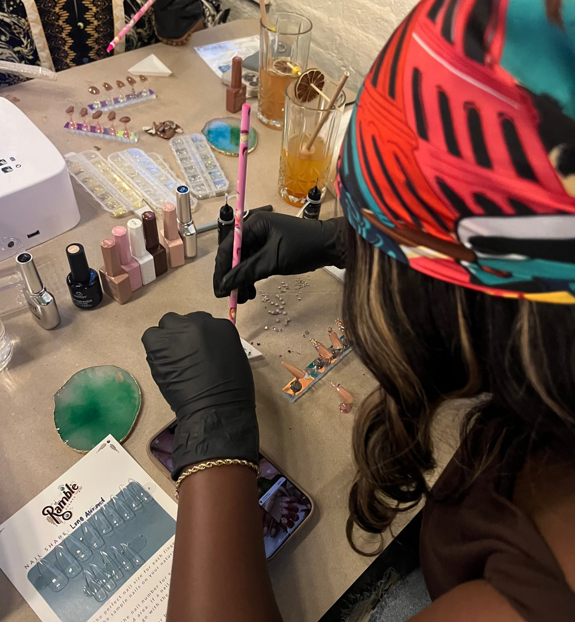 Person applying gems on press on nails with a rhinestone tool